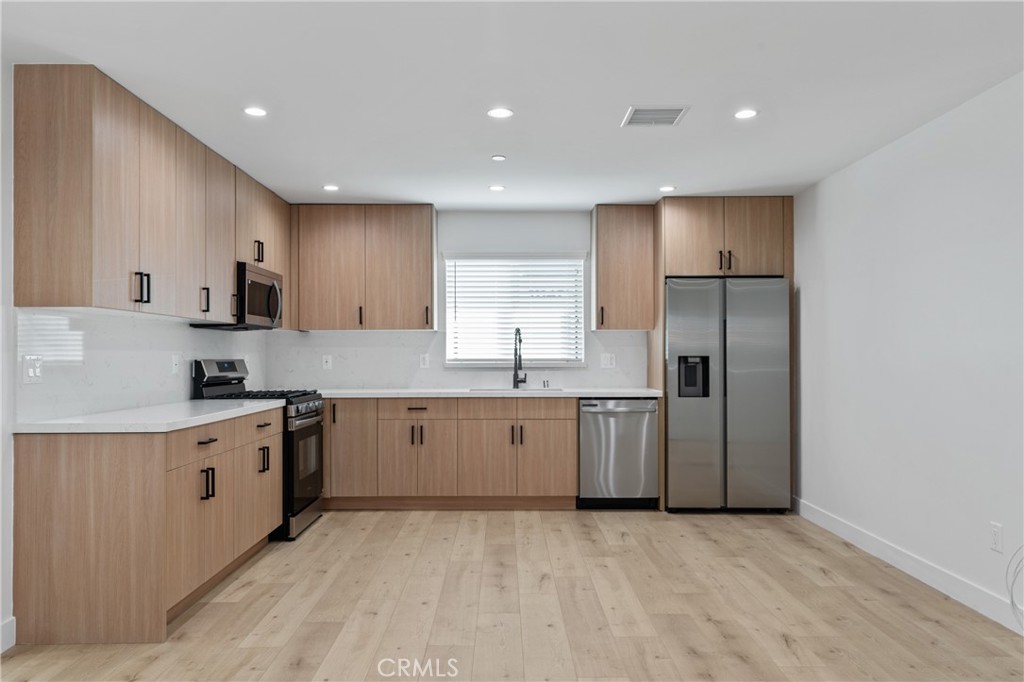 11140 Woodley Avenue, Unit 1/2 Granada Hills, CA 91344 - Photo 8 of 20 a large kitchen with stainless steel appliances granite countertop a stove a sink and a refrigerator