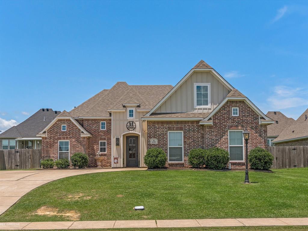 Brick facade with board and batten accents, a prominent gabled entry, and an arched entryway