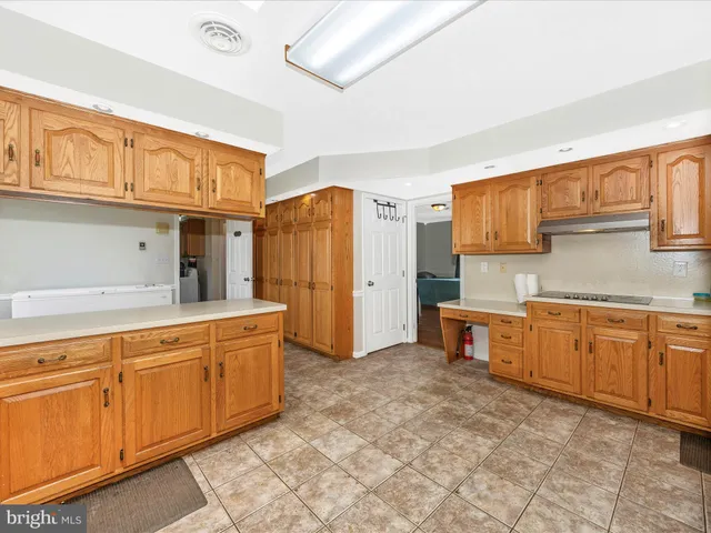 a large kitchen with kitchen island a large window a sink and stainless steel appliances