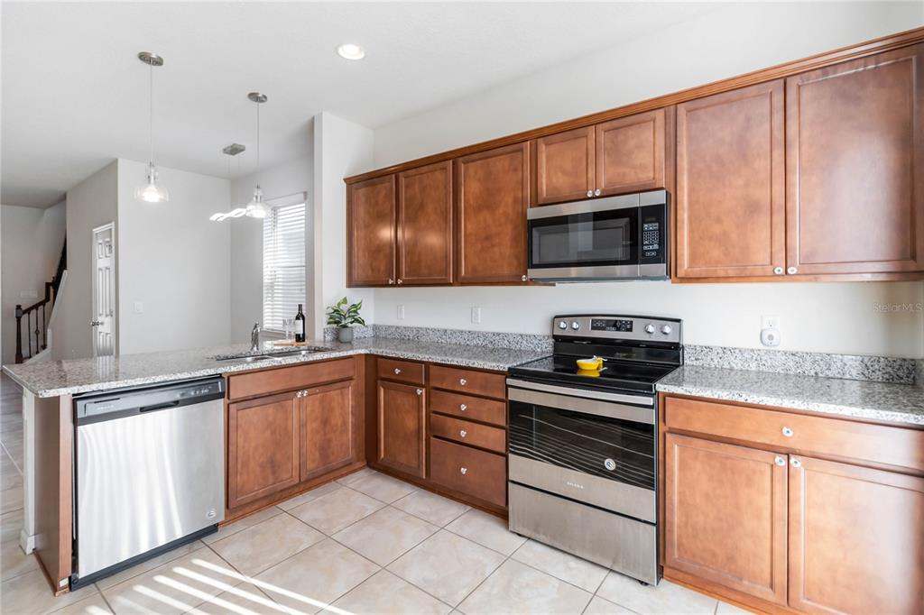 3566 Southern Cross Loop Kissimmee, FL 34744 - Photo 11 of 32 a kitchen with stainless steel appliances granite countertop wooden cabinets a stove and a sink