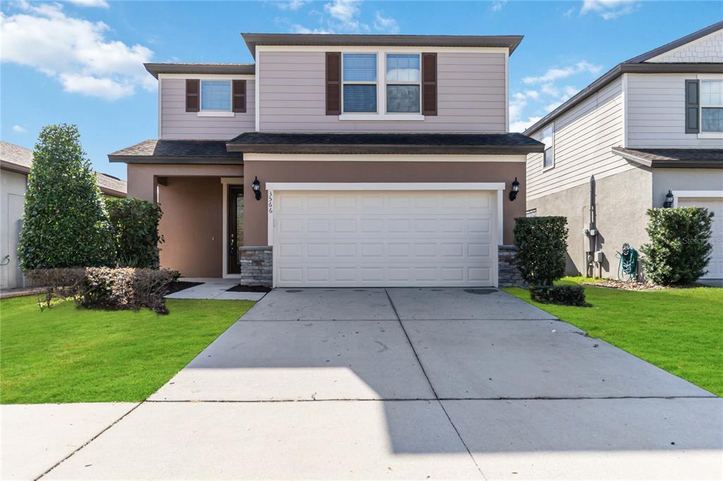 3566 Southern Cross Loop Kissimmee, FL 34744 - Photo 2 of 32 a front view of a house with a yard and a garage