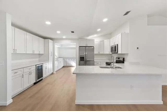 a large white kitchen with kitchen island a sink a stove a refrigerator and white cabinets