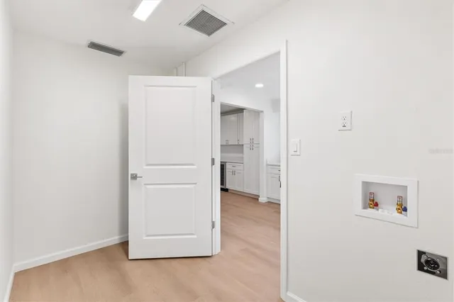 an empty room with kitchen and wooden floor