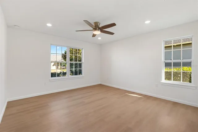 an empty room with windows and fan