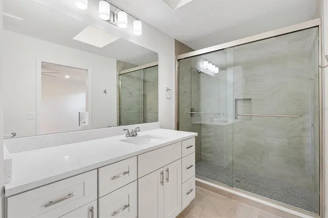 a bathroom with a sink shower and a mirror