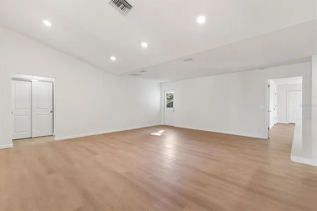 a view of an empty room with wooden floor and closet