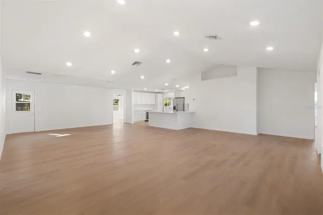 a view of empty room with kitchen and window