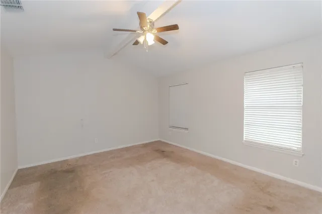 an empty room with a window and a fan