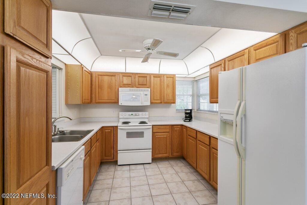 409 Village Drive St. Augustine, FL 32084 - Photo 14 of 75 a kitchen with a sink a refrigerator and cabinets