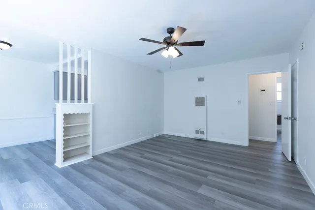 an empty room with wooden floor closet and windows
