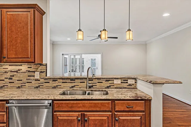 a kitchen with granite countertop a stove a sink and wooden cabinets