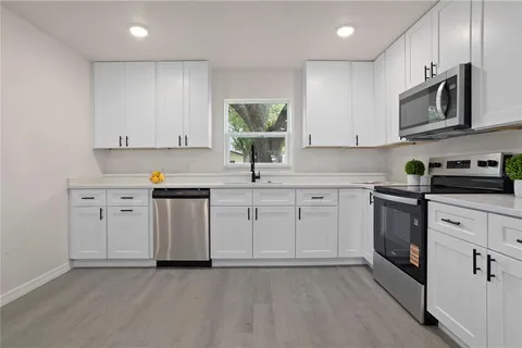 a kitchen with white cabinets stainless steel appliances and sink