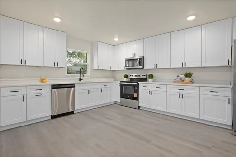 a kitchen with white cabinets stainless steel appliances and sink