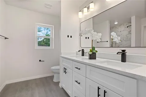 a bathroom with a double vanity sink mirror and toilet