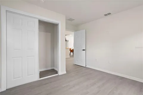 an empty room with wooden floor & windows