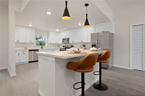 a kitchen with stainless steel appliances granite countertop a sink a stove a refrigerator and island with wooden floor