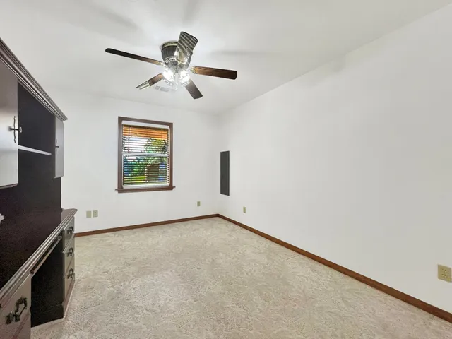 an empty room with window and ceiling fan