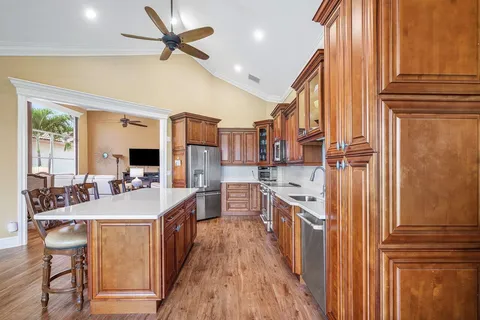 a large kitchen with stainless steel appliances a stove a sink dishwasher and a refrigerator with wooden floor
