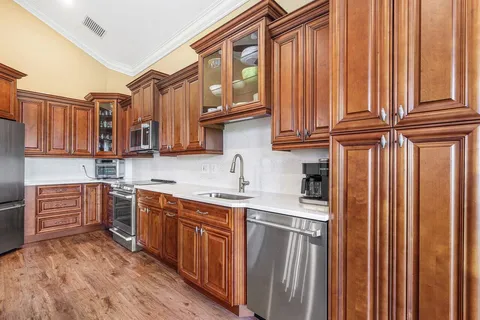 a kitchen with stainless steel appliances granite countertop a sink and dishwasher a refrigerator with wooden cabinets