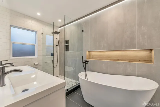 a bathroom with a white tub a sink and a large mirror