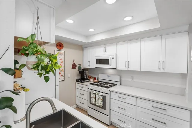 a kitchen with stainless steel appliances a white stove top oven a refrigerator and white cabinets with wooden floor