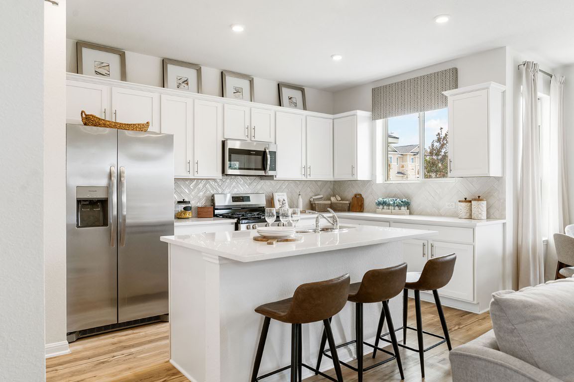 20604 A Haygrazer Way Pflugerville, TX 78660 - Photo 5 of 31 a kitchen with stainless steel appliances a sink a stove a refrigerator cabinets and a dining table with wooden floor