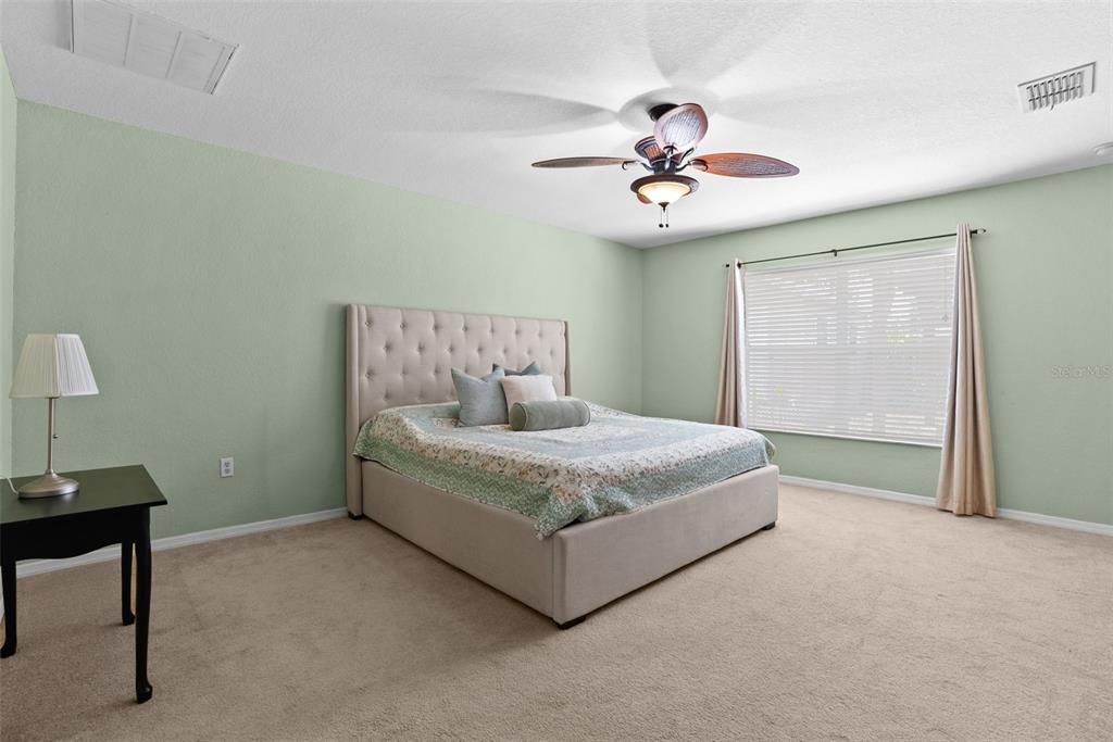 11366 Riddle Drive Spring Hill, FL 34609 - Photo 22 of 49 a spacious bedroom with a bed and a chandelier