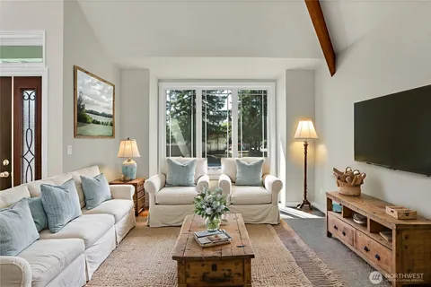 a living room with furniture a flat screen tv and a floor to ceiling window