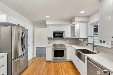 a kitchen with cabinets stainless steel appliances and wooden floor