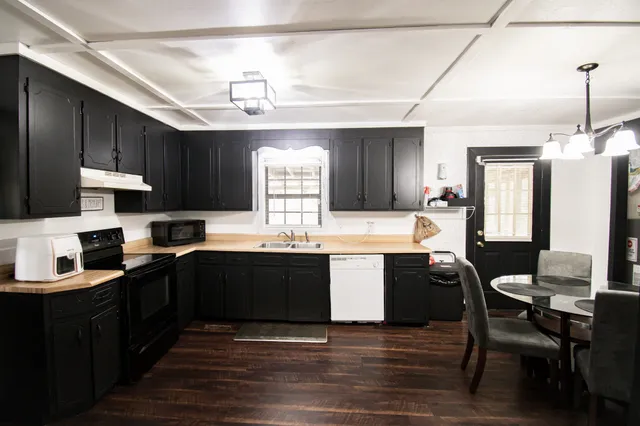 a kitchen with granite countertop a sink cabinets and wooden floor