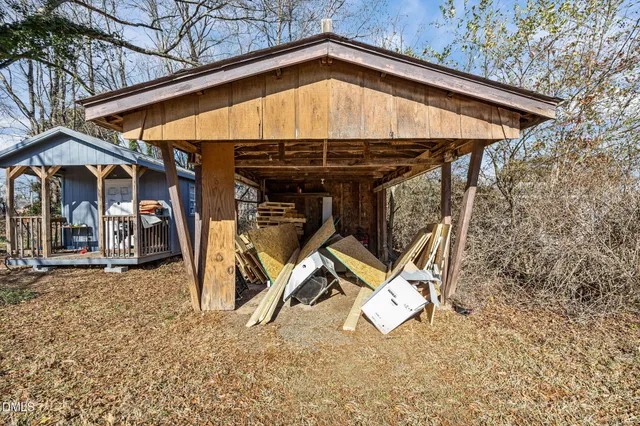 a view of a wooden house with large trees and wooden fence