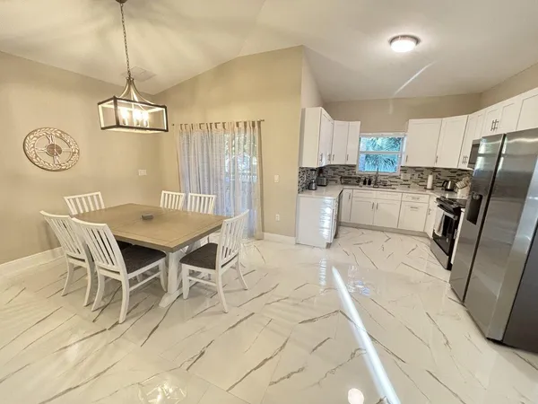 a kitchen with stainless steel appliances granite countertop a stove a refrigerator a kitchen island a table and chairs