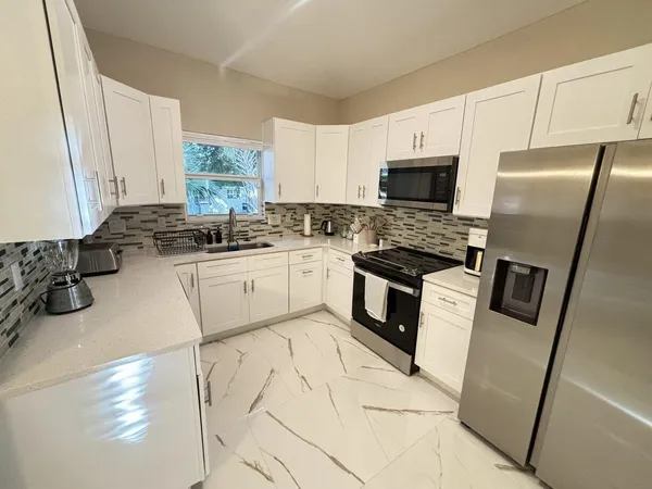 a kitchen with white cabinets sink and stainless steel appliances