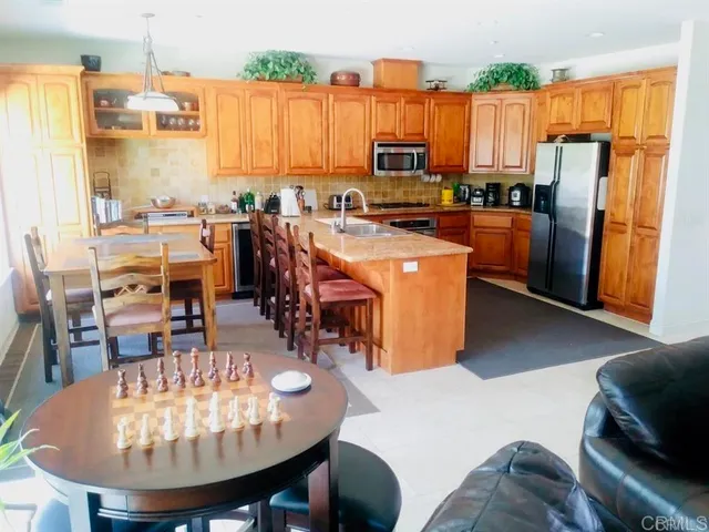 a kitchen with stainless steel appliances kitchen island granite countertop a table chairs and a refrigerator
