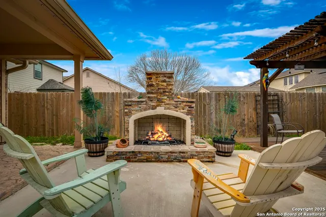 a view of a patio with couches table and chairs under an umbrella with a fire pit