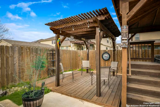 a view of a patio with table and chairs potted plants with wooden floor and fence