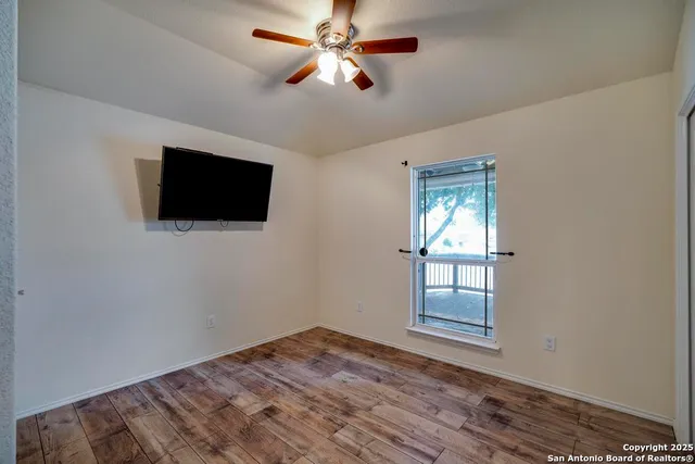 a view of empty room with wooden floor and fan