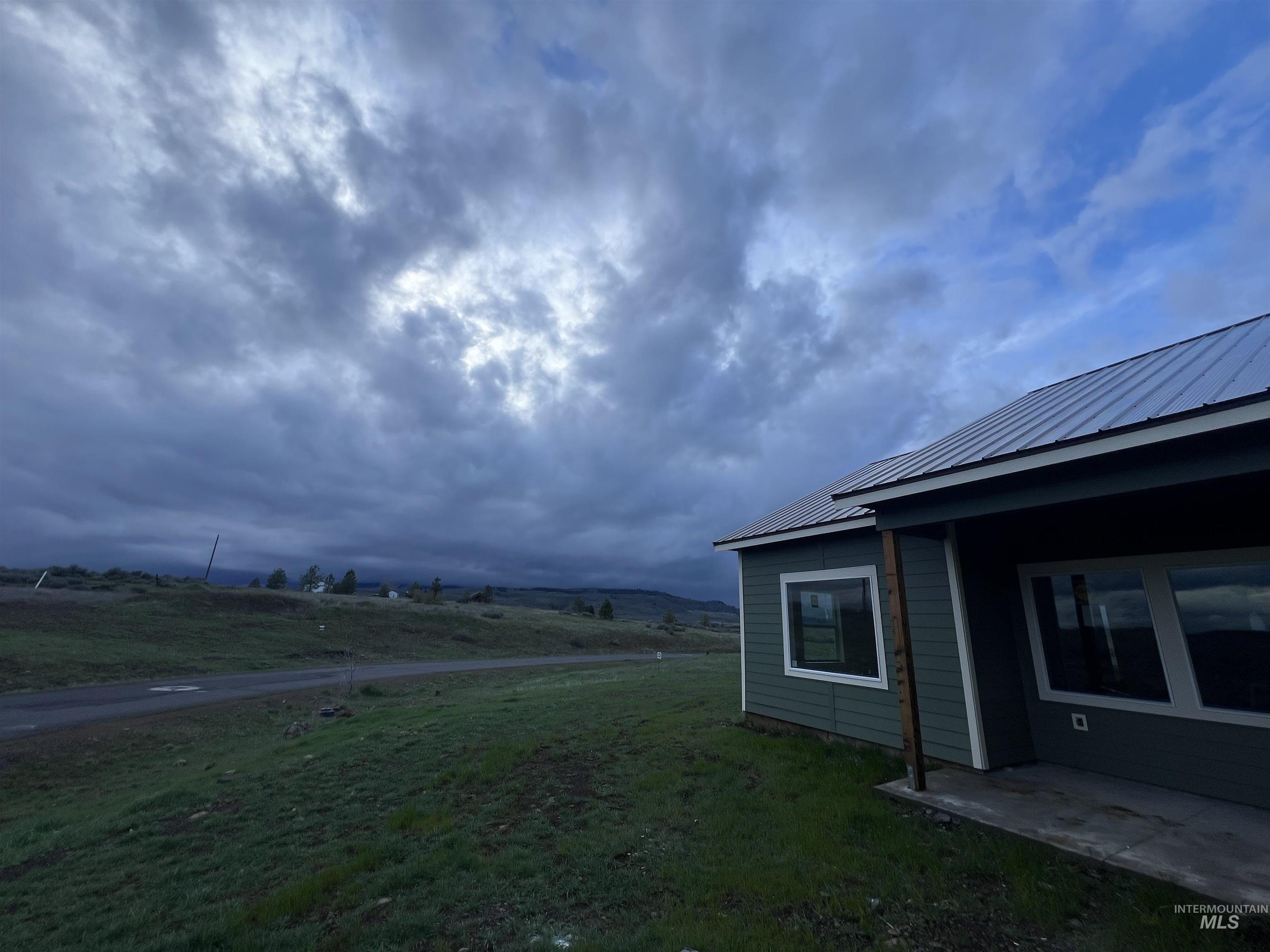 2300 Golf Council, ID 83612 - Photo 2 of 17 Exterior featuring dark green siding, white trim windows, a covered patio, and a metal roof