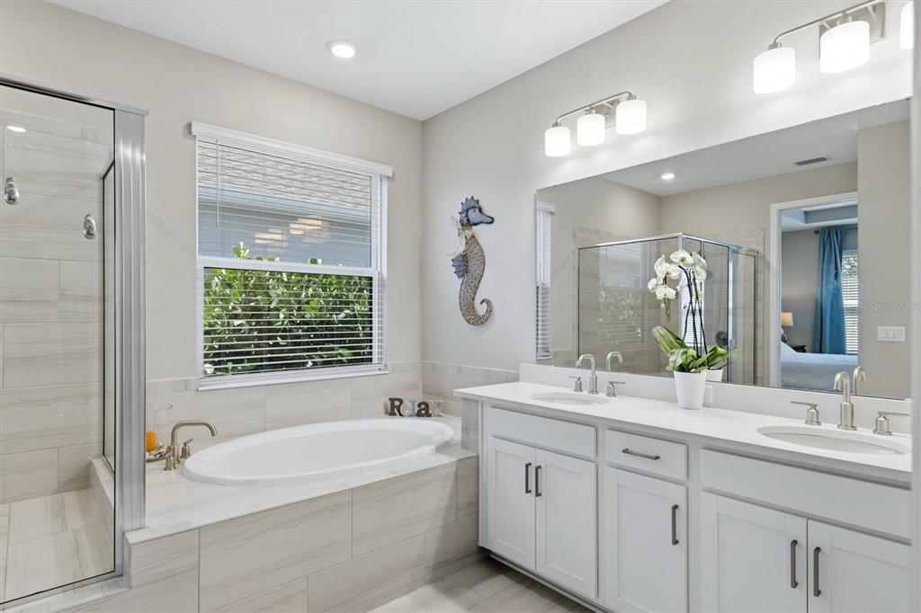 9268 Tequila Sunrise Drive Sarasota, FL 34241 - Photo 22 of 56 a bathroom with a tub a sink double vanity and a mirror