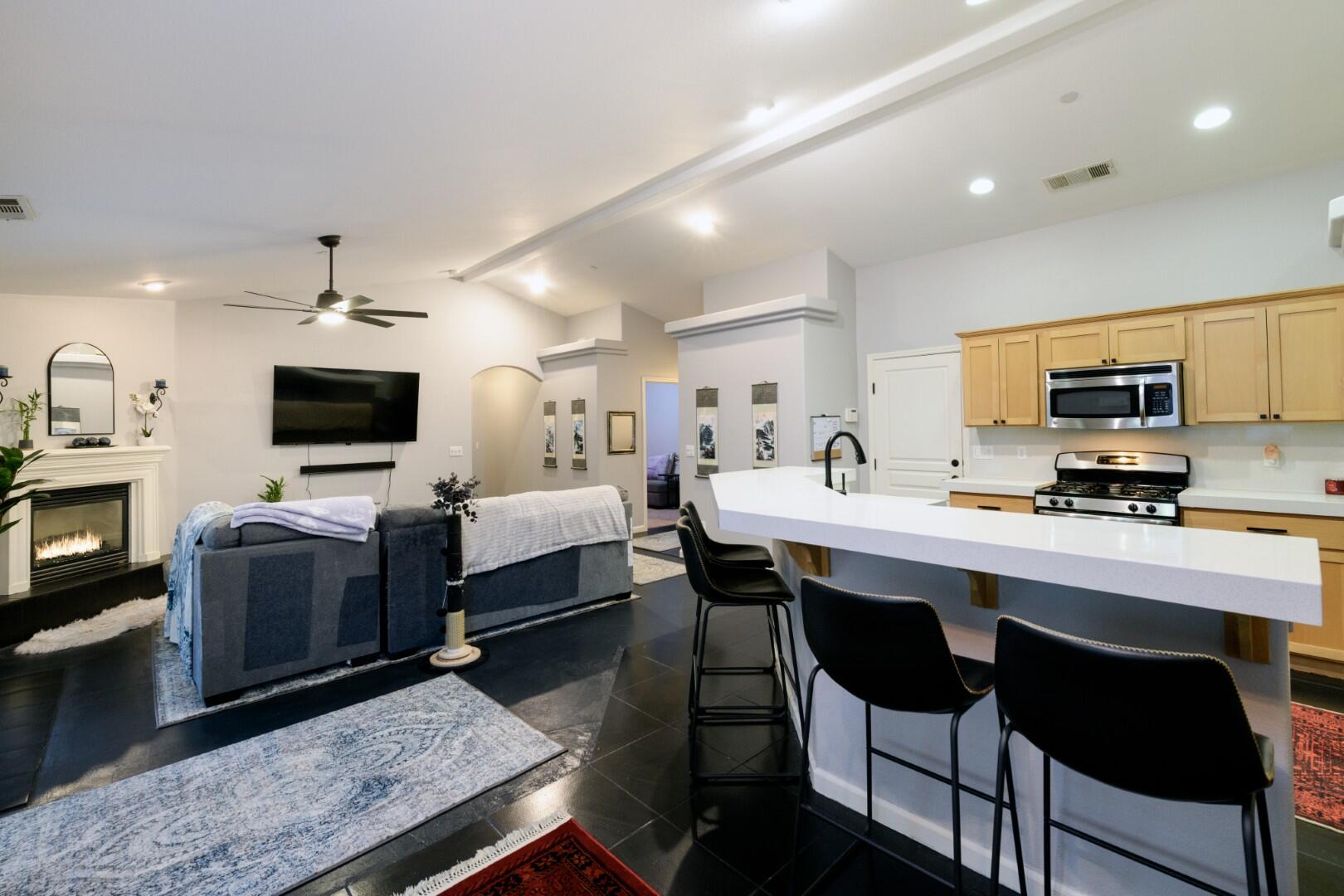 671 Valleybrook Drive Redding, CA 96003 - Photo 3 of 20 a large white kitchen with stainless steel appliances granite countertop a stove a sink dishwasher a dining table and chairs with the wooden floor