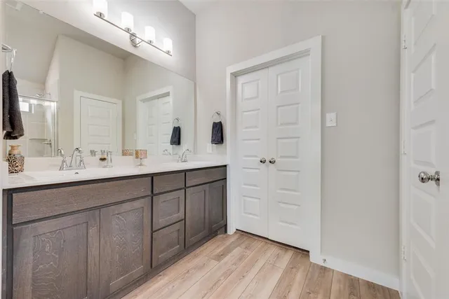 a spacious bathroom with a double vanity sink a mirror and a shower