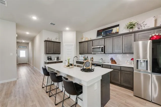 a kitchen with a sink a microwave a refrigerator and chairs