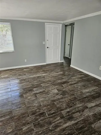 a view of an empty room with wooden floor and a window