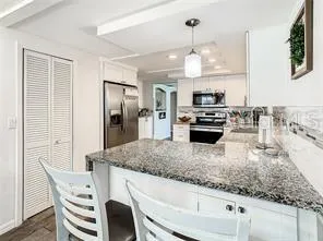 a kitchen with stainless steel appliances granite countertop a kitchen island a stove a table and chairs
