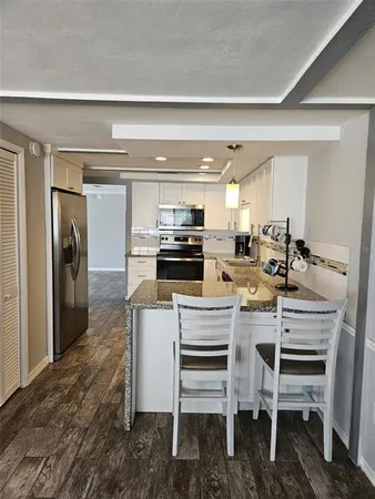 a kitchen with a dining table chairs and refrigerator