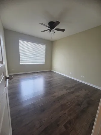 an empty room with wooden floor a ceiling fan and windows