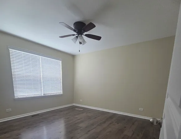 an empty room with a window and a fan