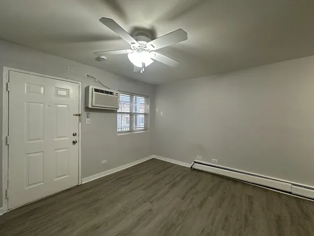 an empty room with wooden floor fan and windows