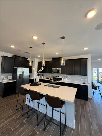 a kitchen with stainless steel appliances kitchen island granite countertop a stove a sink a refrigerator and a microwave