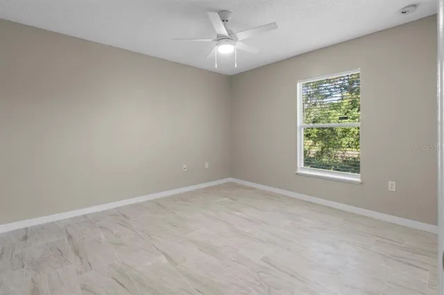 an empty room with a window and a fan